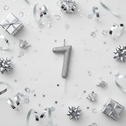 Silver glitter number 7 candle flat lay with silver ribbons gift boxes and silver party decor
