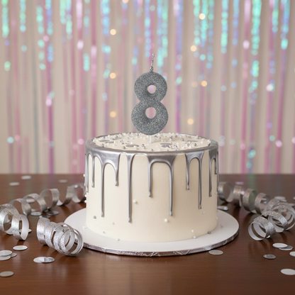 Silver glitter number 8 candle on white cake with silver drip and confetti